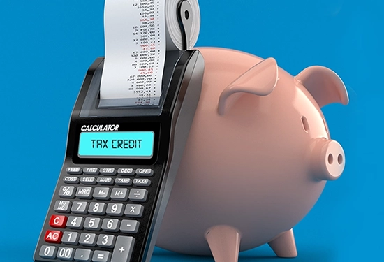 A piggy bank with a calculator leaning against it.